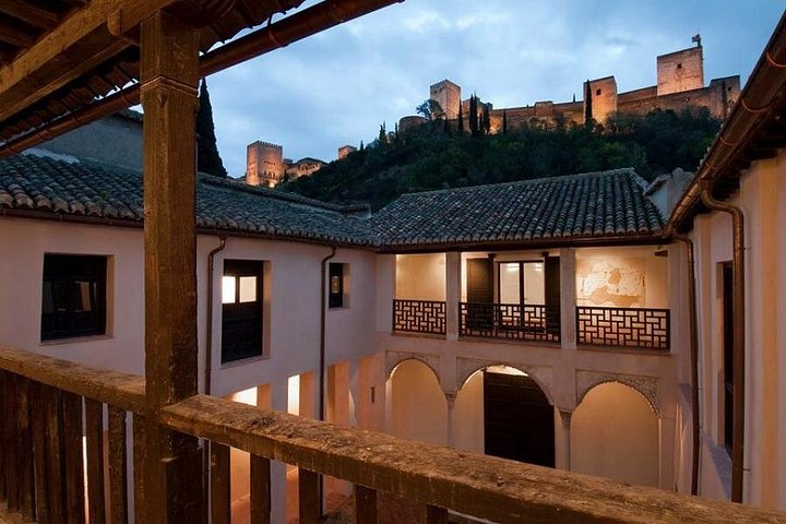 Alhambra towers seen beyond an arcaded courtyard in Albaicín
