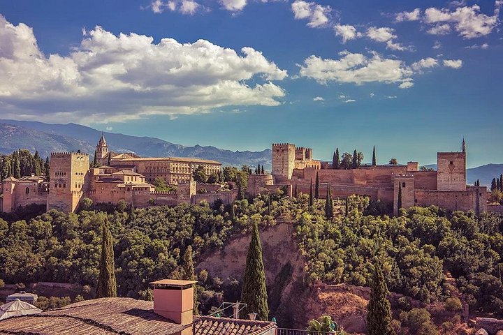 The Alhambra’s long red walls above wooded slopes and Granada rooftops