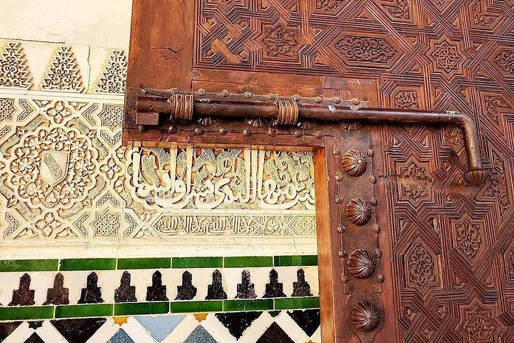 Carved wooden door, Arabic inscriptions and coloured tiles in the Alhambra