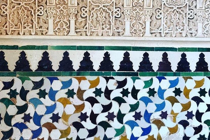 Arabic inscriptions above geometric tilework in the Alhambra