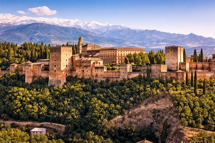 The Alhambra above wooded slopes with snow-capped Sierra Nevada behind