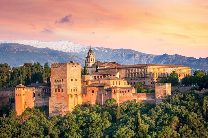 The Alhambra’s towers and palace roofs beneath a pink evening sky